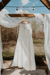 Full length lace wedding dress hanging in the spring sunshine