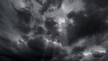 Dark Dramatic Sky With Black Stormy Clouds Before Rain Or Snow As Abstract Background, Extreme Weather, The Sun Shines Through The Clouds, High Contrast Photo