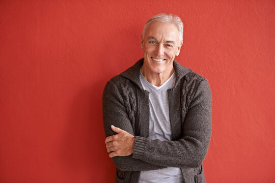 happy senior man, portrait and red background in retirement with smile, arms crossed and fashion. el