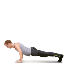 Strength and determination - Fitness. A fit young man doing push-ups on his exercise mat while isolated on white.