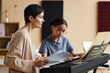 © Seventyfour - Music teacher teaching notes schoolgirl while she learning to play piano in music class