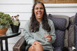 © Austockphoto - Young Aboriginal woman sitting on a couch outside laughing