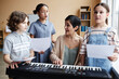 © Seventyfour - Music teacher singing songs together with children while playing piano in music class