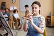 © Seventyfour - Schoolgirl sitting in front of sheet music and learning to play flute in music class