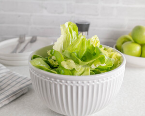 Wall Mural - Plain green salad in a white bowl on light kitchen table 