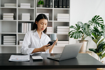 Asian businesswoman working in the modern office with working notepad, tablet and laptop documents