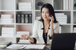 © Kritdanai - Cheerful business lady working on laptop in office, Asian happy beautiful businesswoman in formal suit work in workplace. Attractive female employee office worker smile.