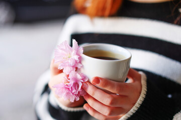 A hand holding cup of coffee decorated with a flower 