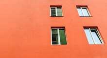 Red Wall Exterior With Four Modern Glass Windows. Deep Orange Stucco Wall Paint.Copy Space.