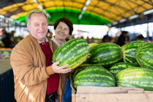 Cheerful Elderly Casual Male And Female Picking Fresh Organic Watermelon At Local Market