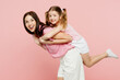 Sideways woman wear casual clothes with child kid girl 6-7 years old. Mother, give piggyback ride to joyful daughter sitting on back isolated on plain pastel pink background Family parent day concept