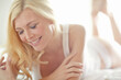 © Grady R/peopleimages.com - One beautiful young smiling blonde woman relaxing on a bed at home. Confident cheerful female feeling flirty, playful, sensual and sexy while posing seductively in white underwear