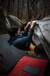 © lightpoet - A rock climber climbing on a boulder rock outdoors. Group of friends involved in sports outside.