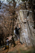 © lightpoet - A rock climber climbing on a boulder rock outdoors. Group of friends involved in sports outside.