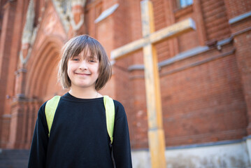 smiling happy child  goes to Sunday school in the temple, stands in front of the Catholic Cathedral