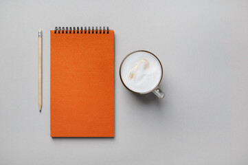 Wall Mural - Photo of blank orange sketchbook, coffee cup and pencil on gray paper background. Flat lay.