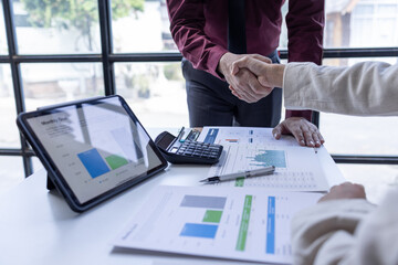 Businessman and businesswoman shaking hands above desk workplace office celebration partnership and successful business deal handshake concept	