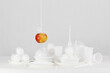 Wiszące na sznurku czerwone jabłko nad plastikowymi jednorazowymi naczyniami 