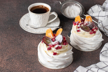 Wall Mural - Mini Pavlova cake with pomegranate, tangerines and grapes on brown background