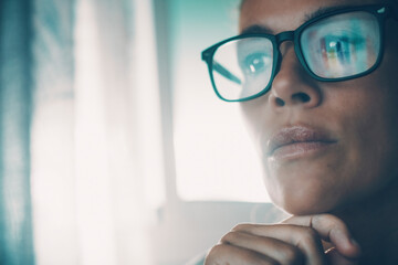 Portrait of thoughtful woman closeup touching her chin and wearing eyeglasses with display light reflection. Adult female face and doubts expression. People thinking for problems solutions. Blue mood