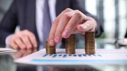 Wall Mural - Man puts a coin on a stack of coins on the table