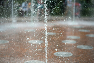 Fountain water jets rising from marble tiles.