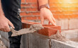 © Iryna - Bricklayer laying brick on cement mix on construction site close-up. Reduce the housing crisis by building more affordable houses concept