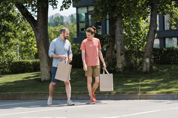 Sticker - bearded father and teenage son walking with shopping bags outdoors.