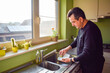 © Mnica - Caucasian mature man washing dishes in the kitchen at home after lunch time. Husband helping wife to clean house. Domestic indoor apartment cleaning routine. People living alone, housekeeping.