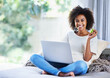 © Mapodile/peopleimages.com - All this surfing is making me hungry. a young woman eating an apple while using her laptop at home.