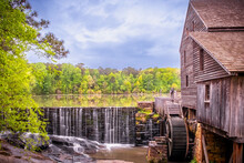Landscape View Of The Millpond, Waterfall, And Gristmill At Historic Yates Mill County Park With Rain Clouds In Raleigh, North Carolina.