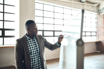 Wall Mural - Coming up with a new plan of action. a businessman using a whiteboard during a presentation in an office.