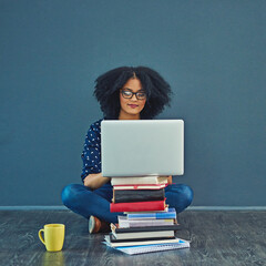 Poster - A grades only for her. Studio shot of a young woman using a laptop with books stacked in front of her against a gray background.