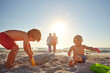 © GR/peopleimages.com - Having some sand fun. two little boys playing on the beach with their parents in the background.