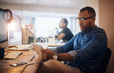 Aufkleber - Making a few smart connections during his late shift. a young businessman using a digital tablet in an office at night.