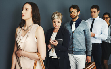 Wall Mural - Waiting in line for a new opportunity. Studio shot of a group of businesspeople waiting in line against a grey background.