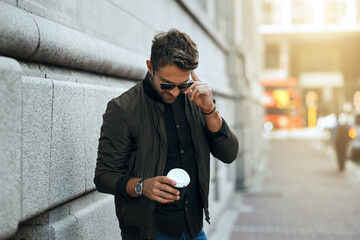 Canvas Print - Alright, Ill wait right here. a handsome young man making a phonecall while traveling through the city.