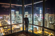 A commercial elite standing at the glass office of the skyscraper looked at the city night view outside the window