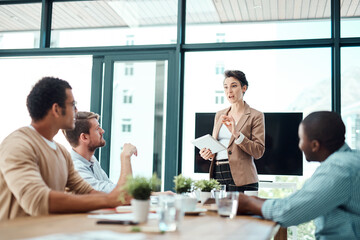 Wall Mural - To answer your question...a young businesswoman giving a presentation to her colleagues in an office.