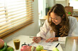 Female nutritionist sitting at working desk with fresh fruit and writing recipe. Healthy food and dieting concept