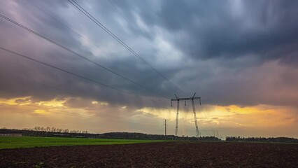 Wall Mural - Golden and stormy dark clouds mixing above power lines poles, time lapse