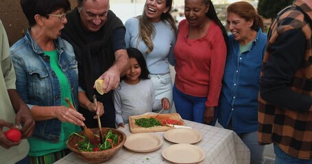 Wall Mural - Group of multiracial friends having fun preparing salad for barbecue at house rooftop - Multi generational people enjoy day together outdoor during weekend day 