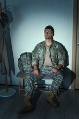 Poster - Lonely military veteran with post traumatic stress disorder sitting in hallway at home at night.