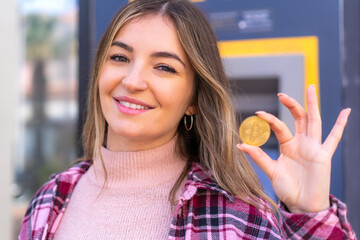 Wall Mural - Young pretty Romanian woman holding a Bitcoin at outdoors