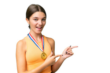 Poster - Teenager caucasian girl with medals over isolated background surprised and pointing side