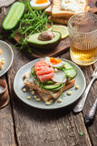 Fototapeta Nowy Jork - toasts with cream cheese, salmon, egg, avocado, cucumber  in a plate