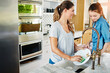 © Reese/peopleimages.com - Who said you cant bond while doing housework. a young mother washing dishes at home while her daughter watches.