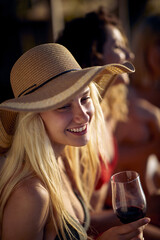 Wall Mural - Young girl drink wine on a dock by the water during sunset