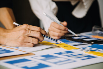 Close up ux developer and ui designer brainstorming about mobile app interface wireframe design on table with customer breif and color code at modern office.Creative digital development agency