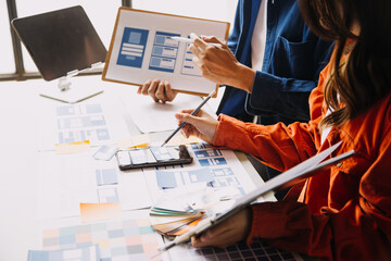 Close up ux developer and ui designer brainstorming about mobile app interface wireframe design on table with customer breif and color code at modern office.Creative digital development agency